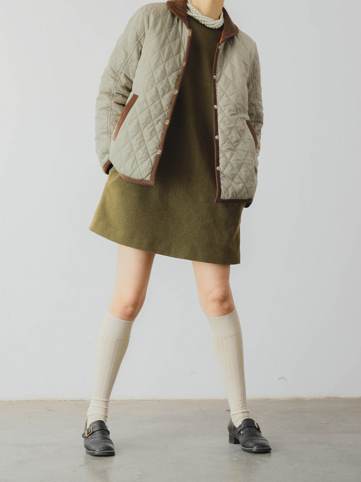 詳細画像: ツートーンのダイヤ柄キルティング加工が施されたコート、ポリエステル素材で軽量かつ耐久性のあるデザイン、ディテールにこだわったアクセント。
モデル画像: スカートやパンツとのコーディネートでイギリス風スクールスタイルを演出したモデルが着用したピーターパンカラーコート。