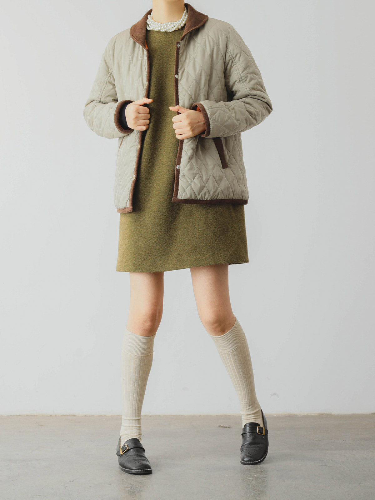 詳細画像: ツートーンのダイヤ柄キルティング加工が施されたコート、ポリエステル素材で軽量かつ耐久性のあるデザイン、ディテールにこだわったアクセント。
モデル画像: スカートやパンツとのコーディネートでイギリス風スクールスタイルを演出したモデルが着用したピーターパンカラーコート。