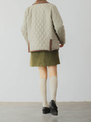 詳細画像: ツートーンのダイヤ柄キルティング加工が施されたコート、ポリエステル素材で軽量かつ耐久性のあるデザイン、ディテールにこだわったアクセント。
モデル画像: スカートやパンツとのコーディネートでイギリス風スクールスタイルを演出したモデルが着用したピーターパンカラーコート。