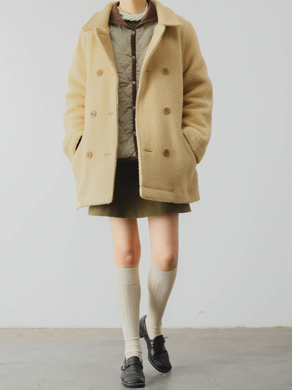 詳細画像: ツートーンのダイヤ柄キルティング加工が施されたコート、ポリエステル素材で軽量かつ耐久性のあるデザイン、ディテールにこだわったアクセント。
モデル画像: スカートやパンツとのコーディネートでイギリス風スクールスタイルを演出したモデルが着用したピーターパンカラーコート。