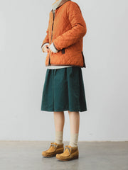 詳細画像: ツートーンのダイヤ柄キルティング加工が施されたコート、ポリエステル素材で軽量かつ耐久性のあるデザイン、ディテールにこだわったアクセント。
モデル画像: スカートやパンツとのコーディネートでイギリス風スクールスタイルを演出したモデルが着用したピーターパンカラーコート。