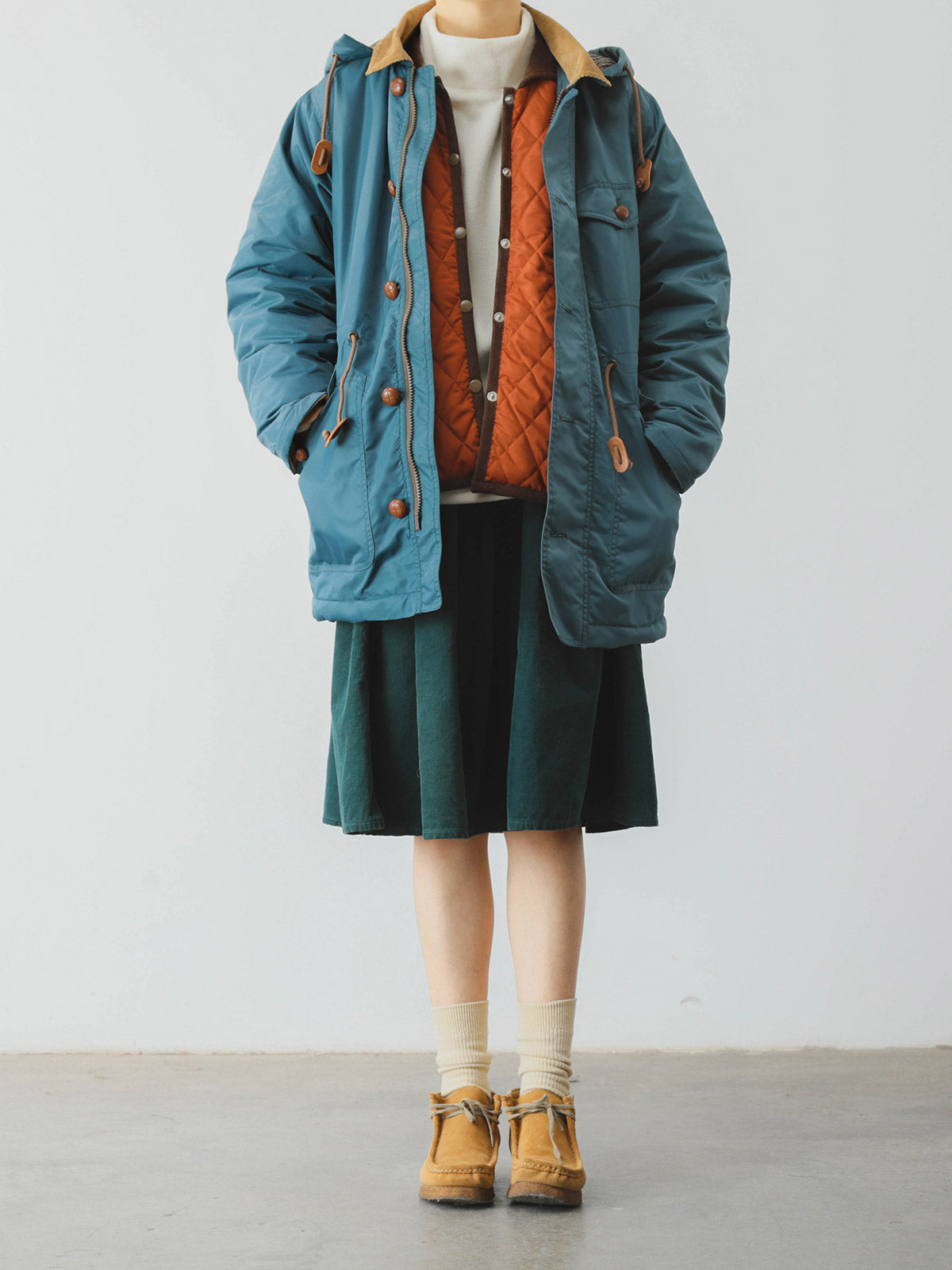 詳細画像: ツートーンのダイヤ柄キルティング加工が施されたコート、ポリエステル素材で軽量かつ耐久性のあるデザイン、ディテールにこだわったアクセント。
モデル画像: スカートやパンツとのコーディネートでイギリス風スクールスタイルを演出したモデルが着用したピーターパンカラーコート。