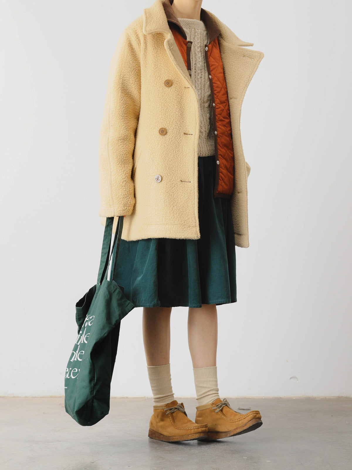 詳細画像: ツートーンのダイヤ柄キルティング加工が施されたコート、ポリエステル素材で軽量かつ耐久性のあるデザイン、ディテールにこだわったアクセント。
モデル画像: スカートやパンツとのコーディネートでイギリス風スクールスタイルを演出したモデルが着用したピーターパンカラーコート。