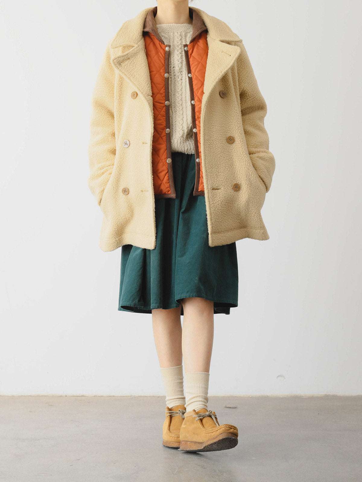 詳細画像: ツートーンのダイヤ柄キルティング加工が施されたコート、ポリエステル素材で軽量かつ耐久性のあるデザイン、ディテールにこだわったアクセント。
モデル画像: スカートやパンツとのコーディネートでイギリス風スクールスタイルを演出したモデルが着用したピーターパンカラーコート。