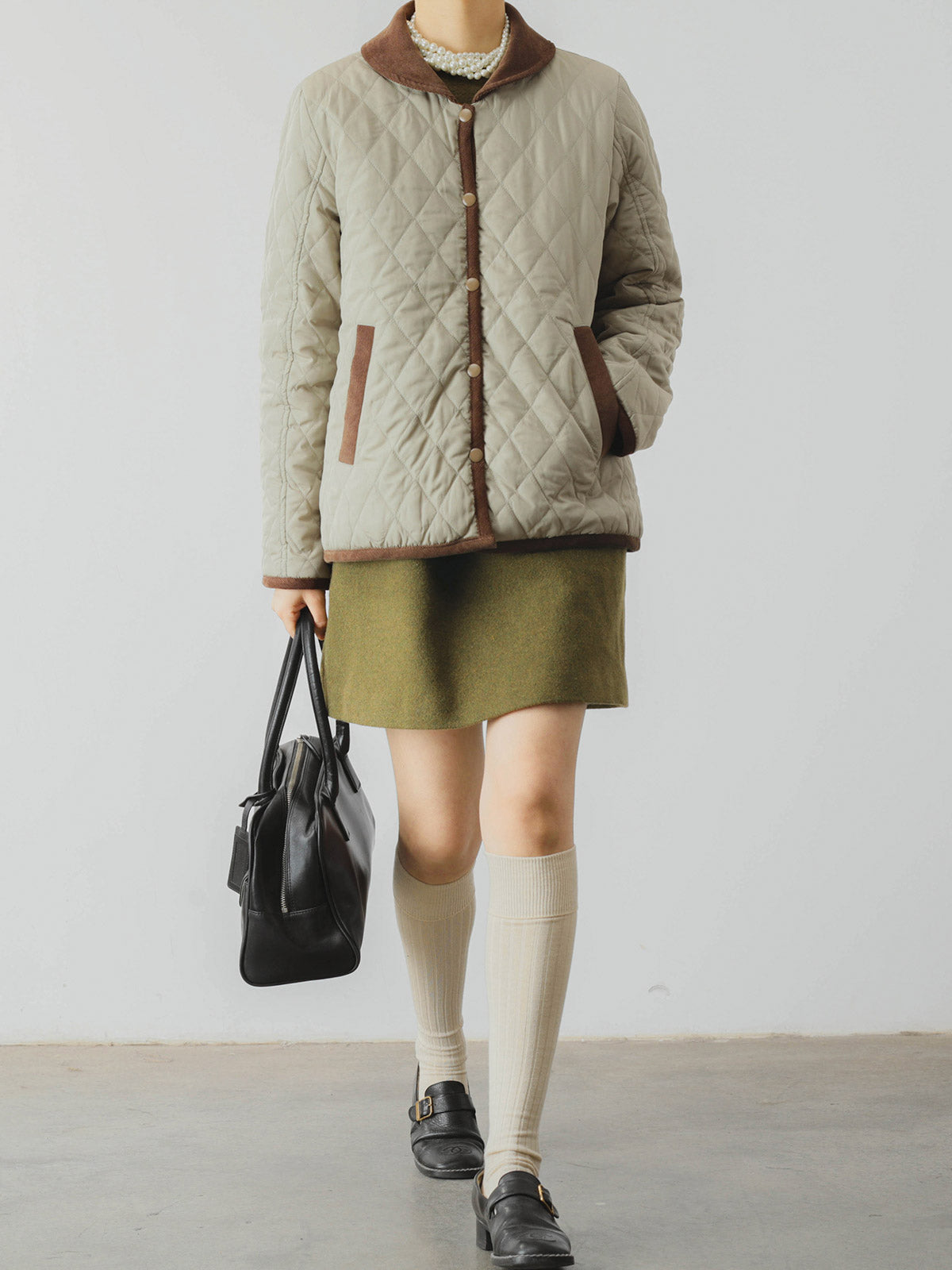 詳細画像: ツートーンのダイヤ柄キルティング加工が施されたコート、ポリエステル素材で軽量かつ耐久性のあるデザイン、ディテールにこだわったアクセント。
モデル画像: スカートやパンツとのコーディネートでイギリス風スクールスタイルを演出したモデルが着用したピーターパンカラーコート。