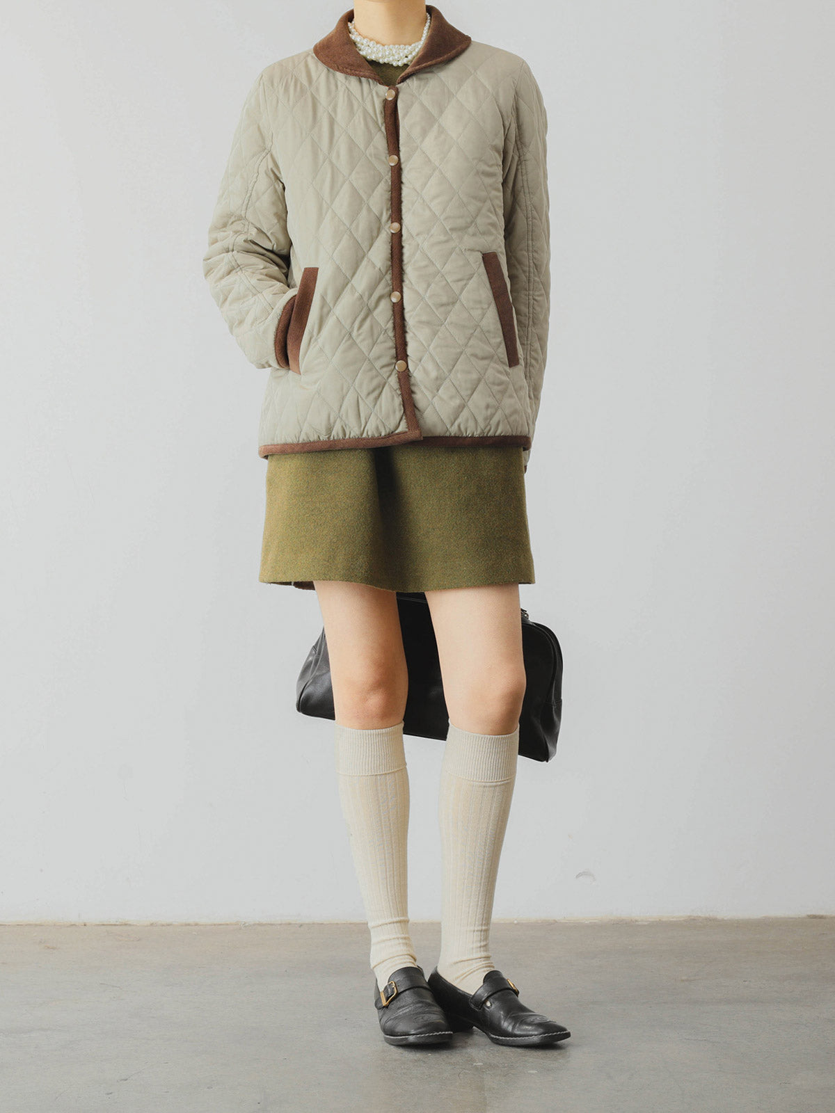 詳細画像: ツートーンのダイヤ柄キルティング加工が施されたコート、ポリエステル素材で軽量かつ耐久性のあるデザイン、ディテールにこだわったアクセント。
モデル画像: スカートやパンツとのコーディネートでイギリス風スクールスタイルを演出したモデルが着用したピーターパンカラーコート。