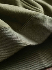 製品画像: フリースタートルネック ミリタリースウェットの全体展示画像。クラシックなタートルネックデザインと3色展開(ミリタリーグリーン、グレー、ブラック)が特徴。WWIIにインスパイアされたミリタリースタイルが際立つ。
詳細画像: 折り返し可能なタートルネック部分と袖まで続くフリース裏地のクローズアップ。防風性と保温性を両立した機能性がわかるディテール。