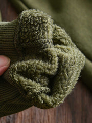 製品画像: フリースタートルネック ミリタリースウェットの全体展示画像。クラシックなタートルネックデザインと3色展開(ミリタリーグリーン、グレー、ブラック)が特徴。WWIIにインスパイアされたミリタリースタイルが際立つ。
詳細画像: 折り返し可能なタートルネック部分と袖まで続くフリース裏地のクローズアップ。防風性と保温性を両立した機能性がわかるディテール。