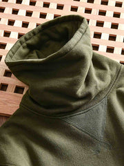 製品画像: フリースタートルネック ミリタリースウェットの全体展示画像。クラシックなタートルネックデザインと3色展開(ミリタリーグリーン、グレー、ブラック)が特徴。WWIIにインスパイアされたミリタリースタイルが際立つ。
詳細画像: 折り返し可能なタートルネック部分と袖まで続くフリース裏地のクローズアップ。防風性と保温性を両立した機能性がわかるディテール。