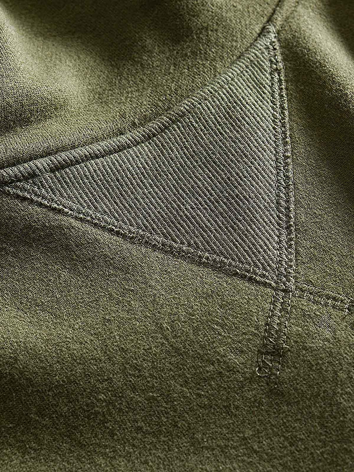 製品画像: フリースタートルネック ミリタリースウェットの全体展示画像。クラシックなタートルネックデザインと3色展開(ミリタリーグリーン、グレー、ブラック)が特徴。WWIIにインスパイアされたミリタリースタイルが際立つ。
詳細画像: 折り返し可能なタートルネック部分と袖まで続くフリース裏地のクローズアップ。防風性と保温性を両立した機能性がわかるディテール。