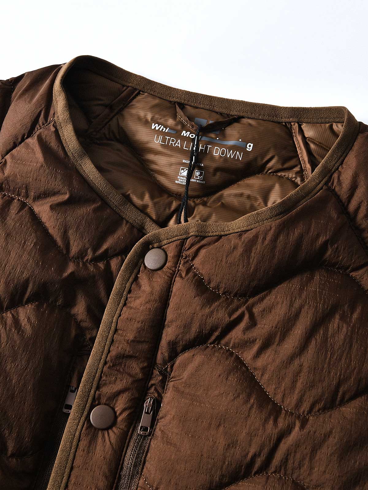 製品画像
ホワイトダックダウン 軽量 ダウンジャケット全体図。シンプルなデザインと700+フィルパワーの高品質ホワイトダックダウンを使用し、軽量で高い保温性を備えた一着。
詳細画像
100%ナイロン素材の防風・撥水性のディテール、高品質90%ホワイトダックダウンとダウン吹き出し防止の縫製、袖口の伸縮仕様の特写。