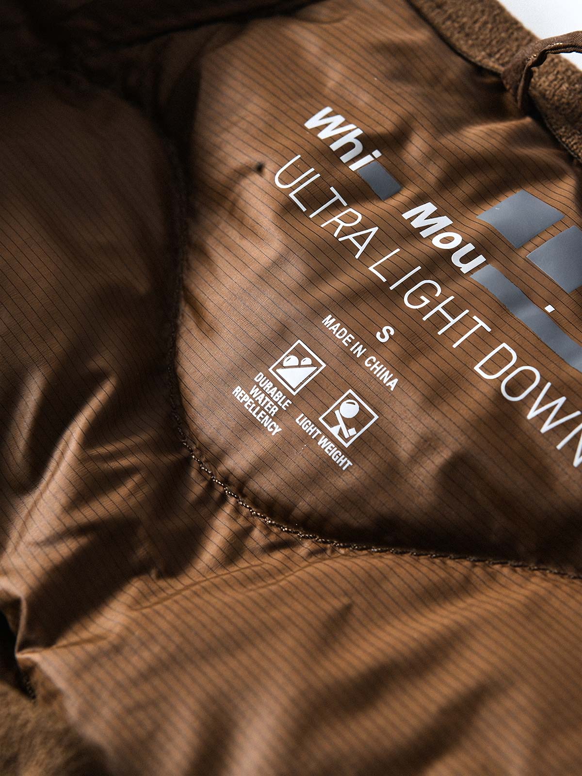 製品画像
ホワイトダックダウン 軽量 ダウンジャケット全体図。シンプルなデザインと700+フィルパワーの高品質ホワイトダックダウンを使用し、軽量で高い保温性を備えた一着。
詳細画像
100%ナイロン素材の防風・撥水性のディテール、高品質90%ホワイトダックダウンとダウン吹き出し防止の縫製、袖口の伸縮仕様の特写。