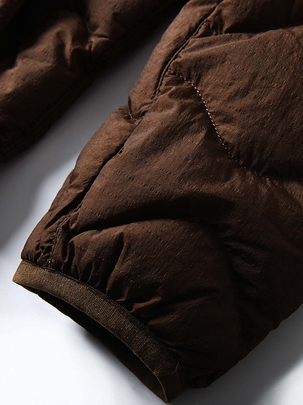 製品画像
ホワイトダックダウン 軽量 ダウンジャケット全体図。シンプルなデザインと700+フィルパワーの高品質ホワイトダックダウンを使用し、軽量で高い保温性を備えた一着。
詳細画像
100%ナイロン素材の防風・撥水性のディテール、高品質90%ホワイトダックダウンとダウン吹き出し防止の縫製、袖口の伸縮仕様の特写。