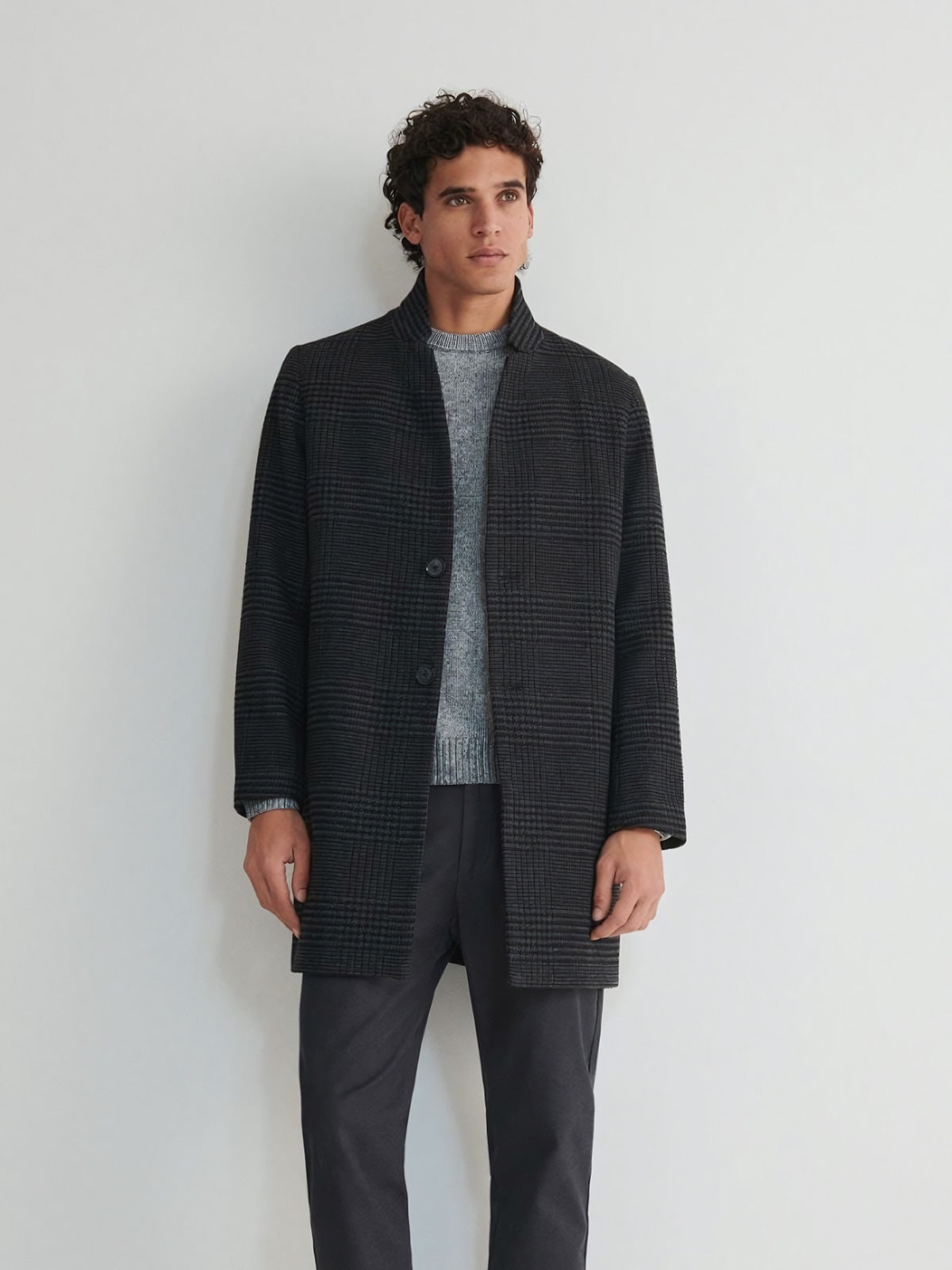 詳細画像
スタンドカラーの防風デザインとクラシックなチェック柄生地のディテールクローズアップ。レトロで洗練された印象を強調。
モデル画像
モデルがスタンドカラー ミドル丈 チェック柄コートを着用し、都会的でエレガントなジェントルマンスタイルを披露。