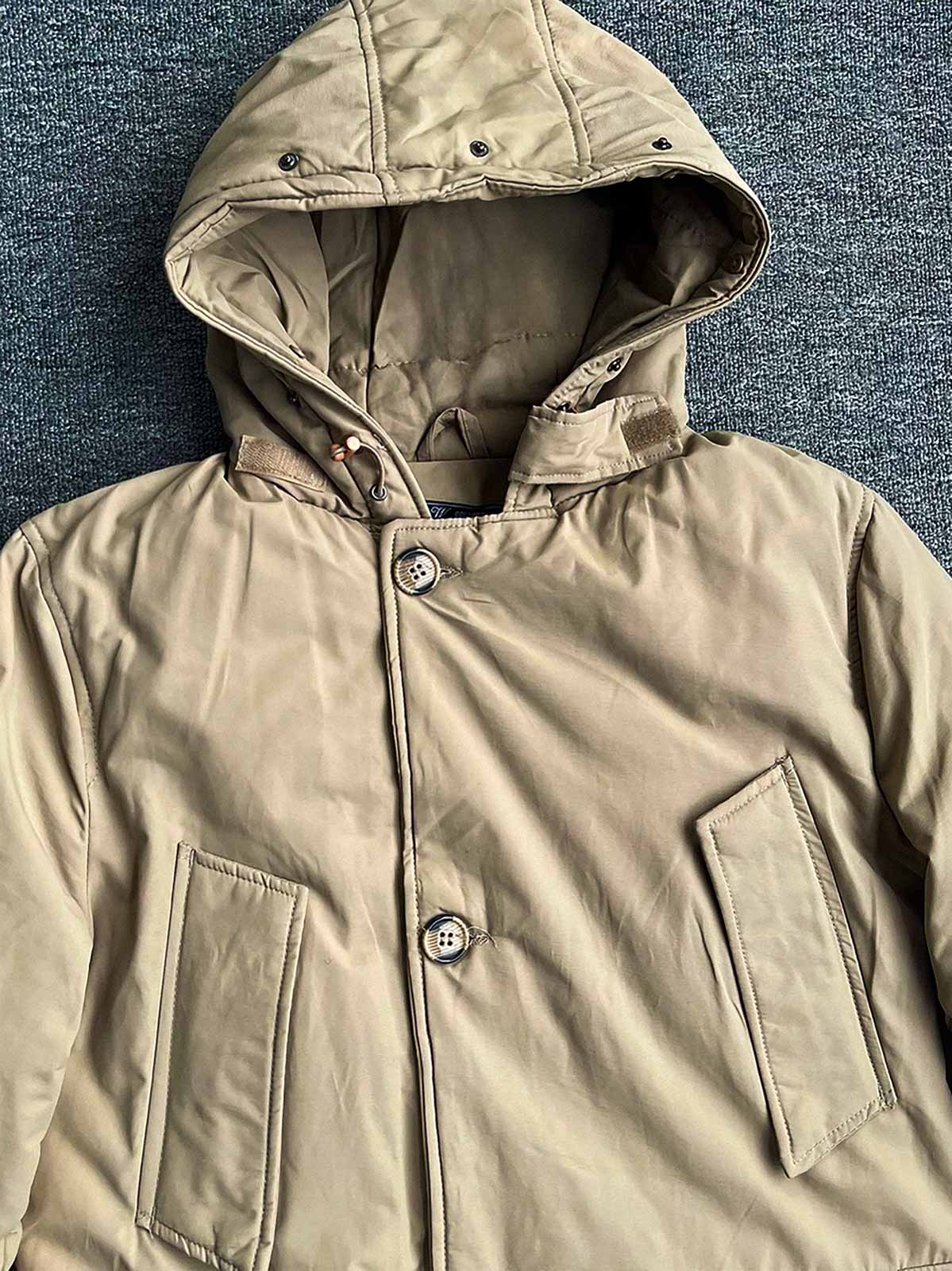 製品画像
「防風性と保温性を兼ね備えたクラシックなフード付きパーカジャケット全体画像。高密度防風素材と加厚ライナーが特徴の秋冬アウター。」
詳細画像
「大容量フラップポケットと高めのスタンドカラーデザインをクローズアップしたディテール画像。フード付き仕様と二重構造のフロントジッパーが防寒性能を強調。」