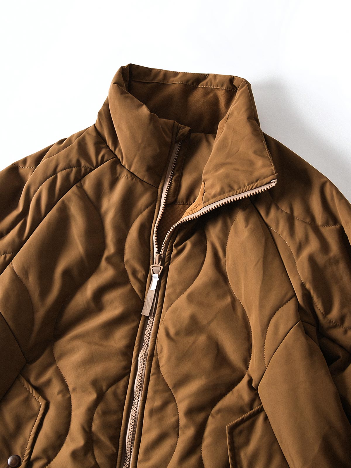 製品画像
「波形キルティングデザインとハイネック仕様が特徴の保温ダウンジャケット正面写真。防風性・保温性・快適性に優れ、静電気防止加工を施したナイロン素材を採用した秋冬に最適なアイテム。」
詳細画像
「フラップ付きの両サイドポケットと背面の通気性メッシュパネルのディテール写真。波形キルティングで中綿が均等に保温性を発揮し、エアダウン素材が快適さを提供するジャケットの特徴を強調した画像。」