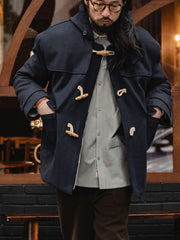 詳細画像
WWI時代のデザインを反映した木製トグルボタンと取り外し可能なストームフラップのディテール。160gウォッシャブルコットン中綿が暖かさと快適さを提供。
モデル画像
モデルがウール混ロング丈フード付きダッフルコートを着用し、冬のヴィンテージ通勤スタイルを演出。クラシックなデザインと現代的な機能性を融合した冬の必須アイテム。