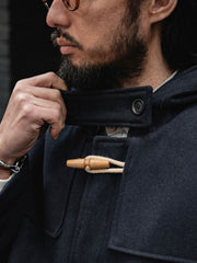 製品画像
ウール混ロング丈フード付きダッフルコート全体イメージ。クラシックな木製トグルボタンと取り外し可能なストームフラップを備え、現代的な保温性能とヴィンテージ感を兼ね備えた一着。
詳細画像
WWI時代のデザインを反映した木製トグルボタンと取り外し可能なストームフラップのディテール。160gウォッシャブルコットン中綿が暖かさと快適さを提供。