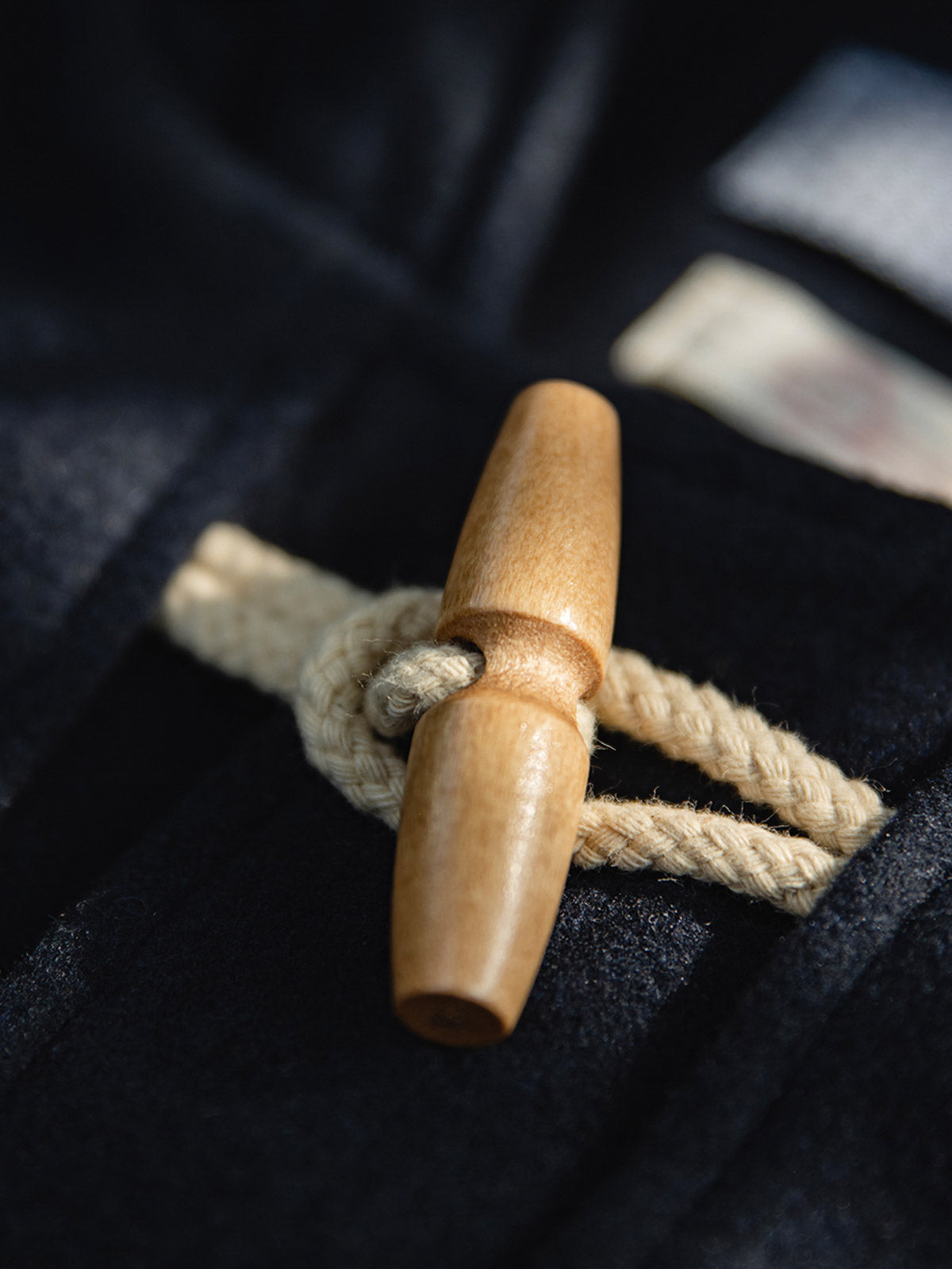 製品画像
ウール混ロング丈フード付きダッフルコート全体イメージ。クラシックな木製トグルボタンと取り外し可能なストームフラップを備え、現代的な保温性能とヴィンテージ感を兼ね備えた一着。
詳細画像
WWI時代のデザインを反映した木製トグルボタンと取り外し可能なストームフラップのディテール。160gウォッシャブルコットン中綿が暖かさと快適さを提供。