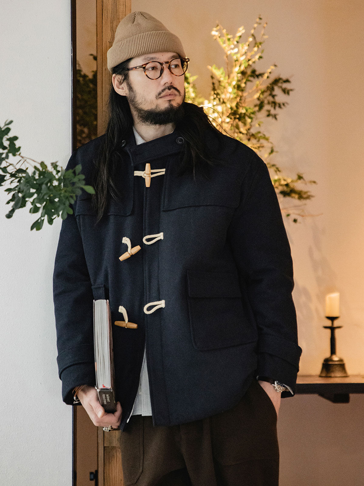 詳細画像
WWI時代のデザインを反映した木製トグルボタンと取り外し可能なストームフラップのディテール。160gウォッシャブルコットン中綿が暖かさと快適さを提供。
モデル画像
モデルがウール混ロング丈フード付きダッフルコートを着用し、冬のヴィンテージ通勤スタイルを演出。クラシックなデザインと現代的な機能性を融合した冬の必須アイテム。