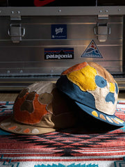 製品画像: 柿渋染め ハンドメイド パッチワーク 刺し子 スカル キャップ。伝統的な染色技術とスカルモチーフのパッチワークデザインが特徴的なキャップの正面全体展示図。
詳細画像: 丁寧な刺し子技術とスカルデザインのパッチワークディテール、自然な粒子感を引き立てる水洗い染色加工のクローズアップ。