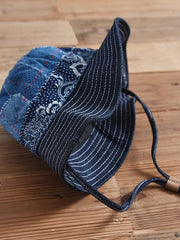 製品画像: ハンドメイド 古布パッチワーク 藍染め 剣道着生地 バケットハット。藍染めと剣道着生地を組み合わせた一点物のバケットハットの全体展示図。
詳細画像: 丁寧なパッチワークディテールと、剣道着生地の風合いを引き立てる細かなステッチのクローズアップ。