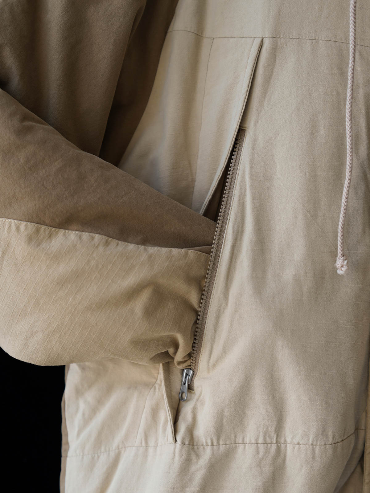 詳細画像
「ペイズリー柄の裏地と日本製YKK製の両開きファスナーのディテールを特写した画像。ヴィンテージデザインと高機能性を兼ね備えたジャケット。」
モデル画像
「モデルがトーンオントーン パッチワーク ミドル丈中綿ジャケットを着用し、デニムパンツと合わせた冬のアウトドアカジュアルスタイルを披露。」