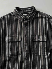 製品画像
「ヘビーフランネル素材を使用したストライプ長袖シャツ全体展示図。ウォッシュ加工によりヴィンテージ感が漂い、クラシックなアメリカンカジュアルスタイルを再現。」
詳細画像
「フランネル素材のテクスチャーと金属ボタンのディテール特写。ウォッシュ加工による自然な風合いと、実用的でデザイン性のある金属ボタンが魅力。」