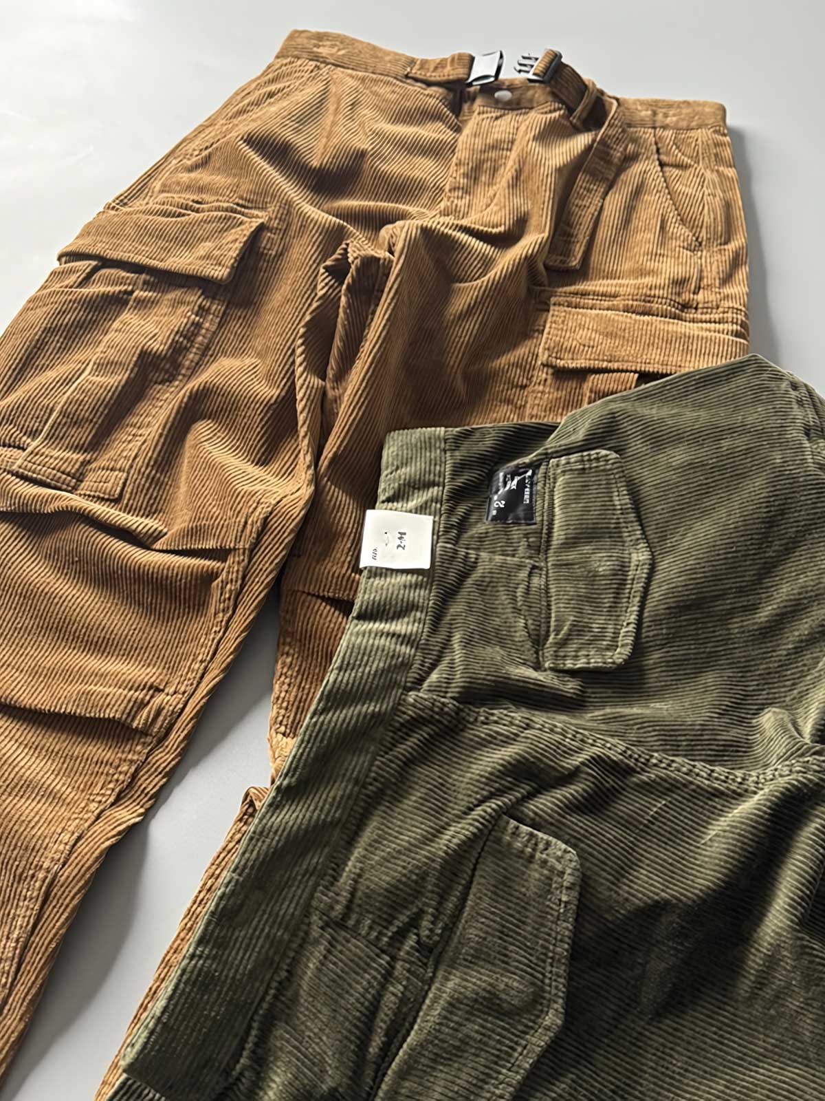 製品画像
「重厚なコーデュロイ素材を使用したカーゴパンツの全体展示図。クラシックなヴィンテージスタイルと快適な履き心地を兼ね備え、テーパードシルエットが脚のラインを美しく見せるデザイン。」
詳細画像
「カーゴパンツの斜め立体ポケットのディテール特写。収納性を高めるだけでなく、全体にカーゴスタイルの立体感を加えたデザイン。」