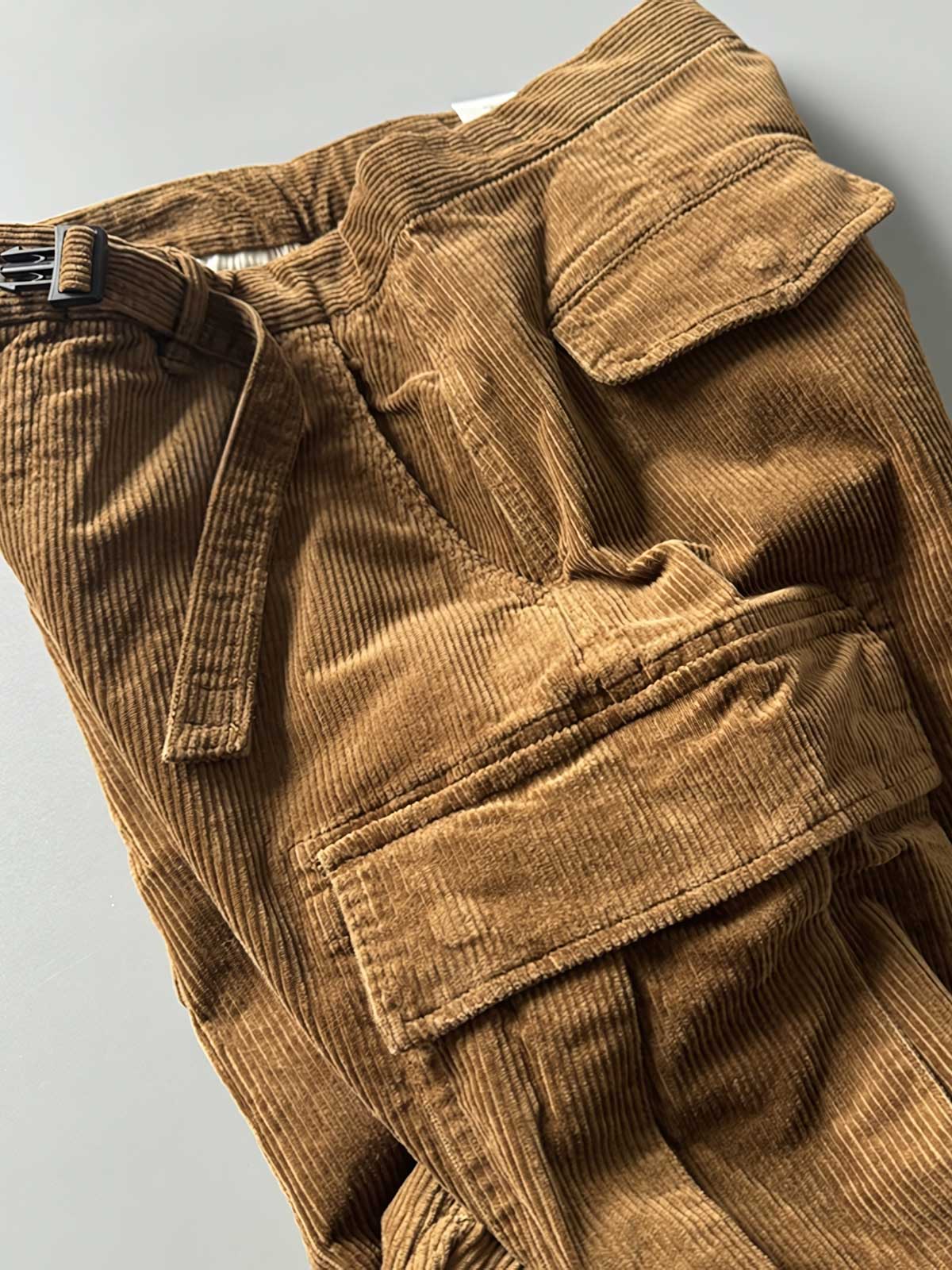 製品画像
「重厚なコーデュロイ素材を使用したカーゴパンツの全体展示図。クラシックなヴィンテージスタイルと快適な履き心地を兼ね備え、テーパードシルエットが脚のラインを美しく見せるデザイン。」
詳細画像
「カーゴパンツの斜め立体ポケットのディテール特写。収納性を高めるだけでなく、全体にカーゴスタイルの立体感を加えたデザイン。」