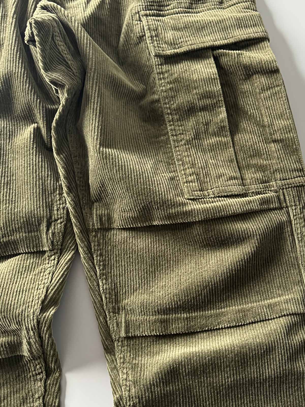 製品画像
「重厚なコーデュロイ素材を使用したカーゴパンツの全体展示図。クラシックなヴィンテージスタイルと快適な履き心地を兼ね備え、テーパードシルエットが脚のラインを美しく見せるデザイン。」
詳細画像
「カーゴパンツの斜め立体ポケットのディテール特写。収納性を高めるだけでなく、全体にカーゴスタイルの立体感を加えたデザイン。」