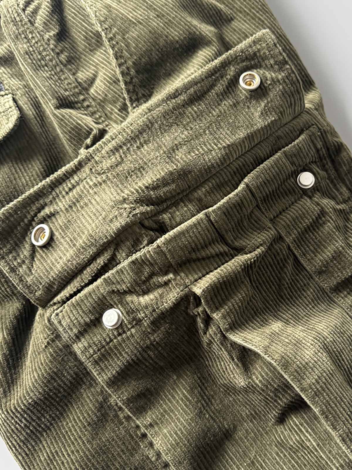 製品画像
「重厚なコーデュロイ素材を使用したカーゴパンツの全体展示図。クラシックなヴィンテージスタイルと快適な履き心地を兼ね備え、テーパードシルエットが脚のラインを美しく見せるデザイン。」
詳細画像
「カーゴパンツの斜め立体ポケットのディテール特写。収納性を高めるだけでなく、全体にカーゴスタイルの立体感を加えたデザイン。」