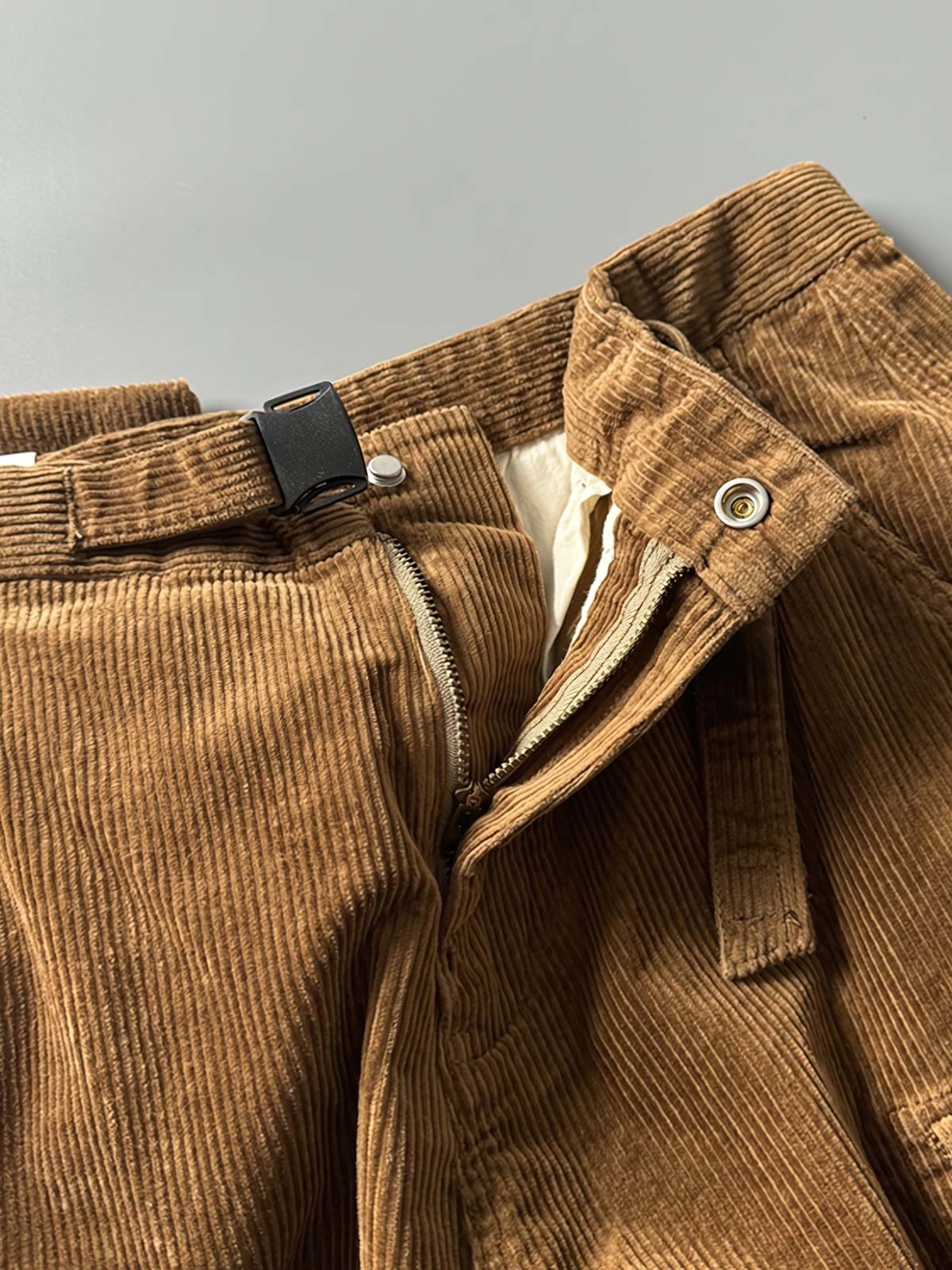 製品画像
「重厚なコーデュロイ素材を使用したカーゴパンツの全体展示図。クラシックなヴィンテージスタイルと快適な履き心地を兼ね備え、テーパードシルエットが脚のラインを美しく見せるデザイン。」
詳細画像
「カーゴパンツの斜め立体ポケットのディテール特写。収納性を高めるだけでなく、全体にカーゴスタイルの立体感を加えたデザイン。」