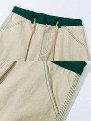 製品画像: 厚手キャンバスワークパンツの正面展示図。高密度キャンバス生地を使用した丈夫な素材感とシンプルでシャープなストレートシルエット。
詳細画像: ワークパンツのカラーブロックデザイン、ウエスト部分のドローコードによる調節機能とサイドポケットのディテール。