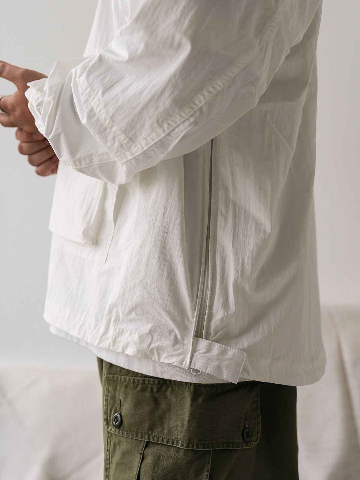 詳細画像
胸元や肩部分に施された立体的なラインデザイン、繊細なグリッド模様、そしてYKK製のマット仕上げファスナーを搭載したポケットの特写。機能性とデザイン性を両立したミリタリースタイルが際立つディテール。
モデル画像
オーバーサイズのシルエットでレイヤードスタイルを楽しめる、多ポケットジャケットを着用したモデルのアウトドアコーディネート。タウンユースやキャンプシーンでの汎用性の高さが映えるスタイル。