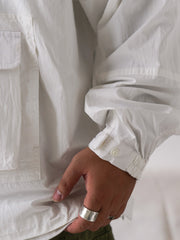 詳細画像
胸元や肩部分に施された立体的なラインデザイン、繊細なグリッド模様、そしてYKK製のマット仕上げファスナーを搭載したポケットの特写。機能性とデザイン性を両立したミリタリースタイルが際立つディテール。
モデル画像
オーバーサイズのシルエットでレイヤードスタイルを楽しめる、多ポケットジャケットを着用したモデルのアウトドアコーディネート。タウンユースやキャンプシーンでの汎用性の高さが映えるスタイル。