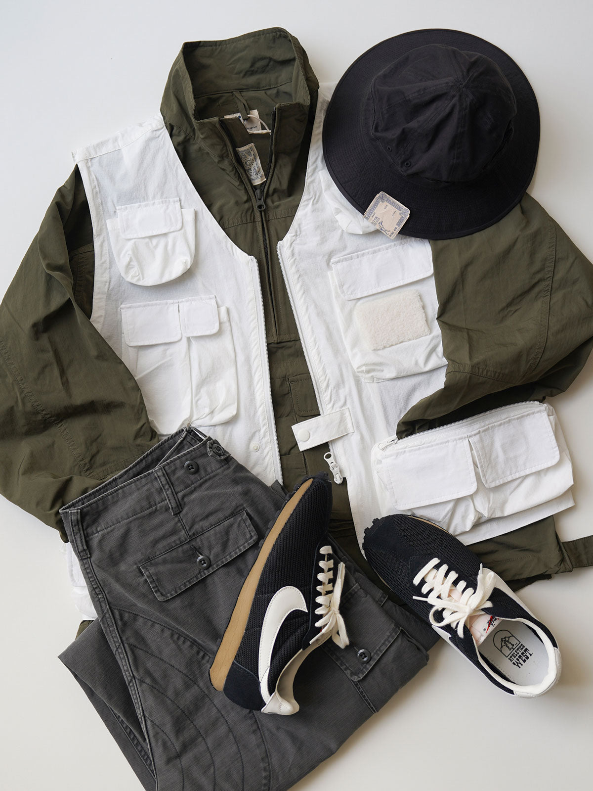 製品画像
軽量で耐久性に優れたナイロンとポリエステルの混紡素材を使用した、多ポケットハーフジップジャケットの全体展示。ヴィンテージ感あふれるデザインと実用的な収納性を備え、アウトドアや日常使いに最適なスタイリッシュなアイテム。
詳細画像
胸元や肩部分に施された立体的なラインデザイン、繊細なグリッド模様、そしてYKK製のマット仕上げファスナーを搭載したポケットの特写。機能性とデザイン性を両立したミリタリースタイルが際立つディテール。