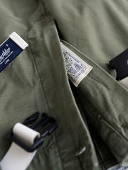 製品画像
ヴィンテージ感漂うバティック染めが特徴の多ポケットロングパンツ全体画像。ミリタリーテイストを取り入れ、300gのコットンサテン生地で耐久性と実用性を兼ね備えたデザイン。
詳細画像
バティック染めによる独特なテクスチャーや、取り外し可能なナイロンベルト、UTX Duraflexバックル、そして膝部分の補強パッチとYKK製カスタムジッパーのディテールショット。高い機能性が際立つ細部。