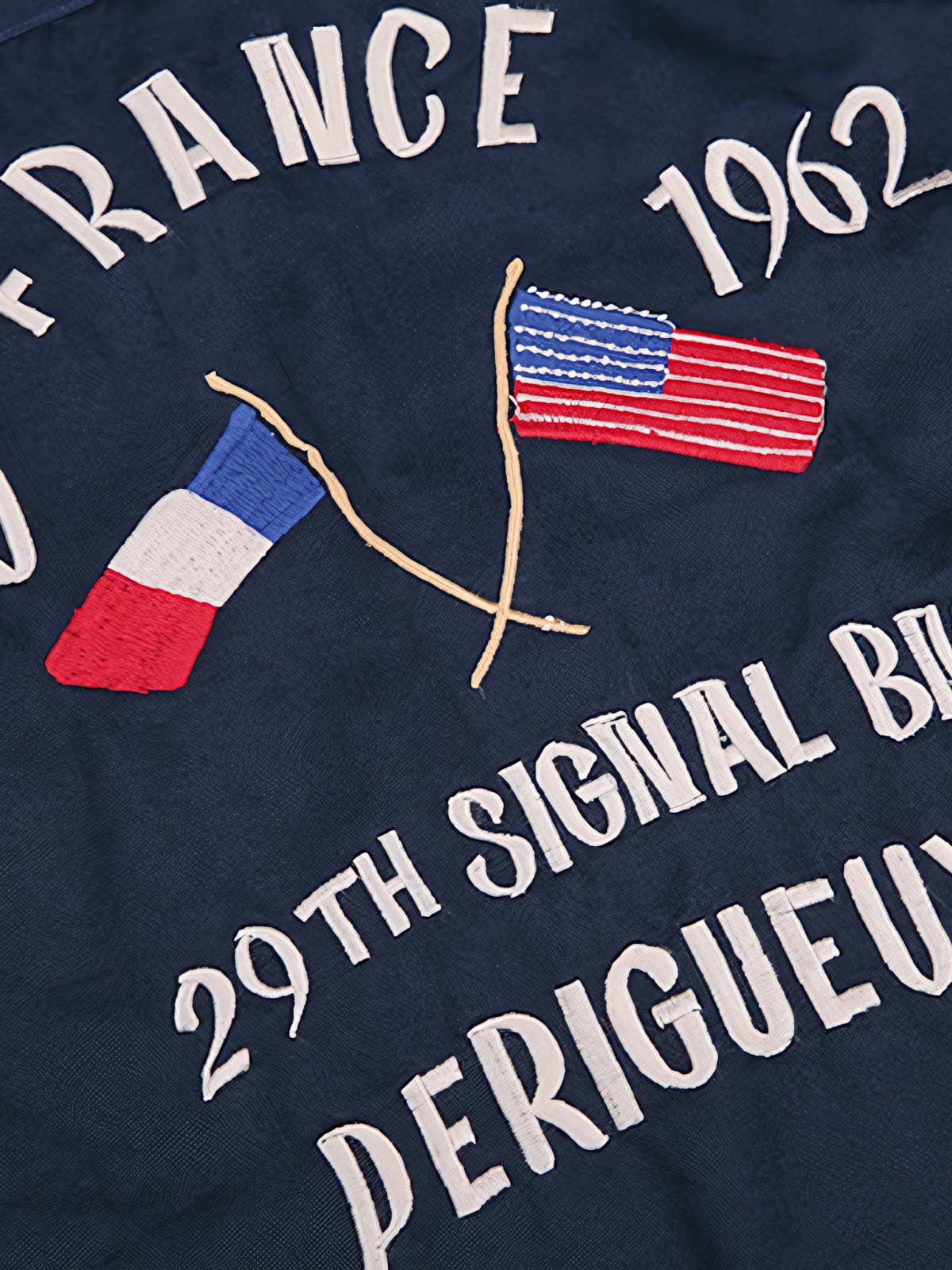 製品画像
厚手キャンバス生地で作られた刺繍キャンバスシャツの全体画像。1960年代のミリタリーユニフォームを再現したヴィンテージ感あるデザインが特徴。
詳細画像
フランス・ペリグーとアメリカ・カリフォルニア州をモチーフにした繊細な刺繍ディテールのクローズアップ。実用的なフラップ付きポケットも強調。