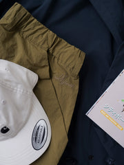 製品画像
撥水性に優れたナイロン素材を使用し、シワ感テクスチャーが特徴のミリタリーパラシュートパンツ全体画像。ダブルプリーツと多機能ポケットを備えたクラシックなシルエットが際立つデザイン。
詳細画像
膝部分のダブルプリーツディテール、隠しポケット、UTX Duraflexドローコードエンド、そして反戦をテーマにしたデュポン紙ラベルのクローズアップ画像。機能性とディテールへのこだわりを強調。