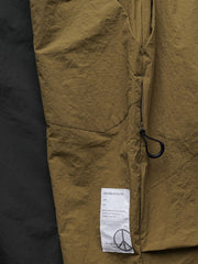 製品画像
撥水性に優れたナイロン素材を使用し、シワ感テクスチャーが特徴のミリタリーパラシュートパンツ全体画像。ダブルプリーツと多機能ポケットを備えたクラシックなシルエットが際立つデザイン。
詳細画像
膝部分のダブルプリーツディテール、隠しポケット、UTX Duraflexドローコードエンド、そして反戦をテーマにしたデュポン紙ラベルのクローズアップ画像。機能性とディテールへのこだわりを強調。