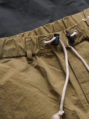 製品画像
撥水性に優れたナイロン素材を使用し、シワ感テクスチャーが特徴のミリタリーパラシュートパンツ全体画像。ダブルプリーツと多機能ポケットを備えたクラシックなシルエットが際立つデザイン。
詳細画像
膝部分のダブルプリーツディテール、隠しポケット、UTX Duraflexドローコードエンド、そして反戦をテーマにしたデュポン紙ラベルのクローズアップ画像。機能性とディテールへのこだわりを強調。