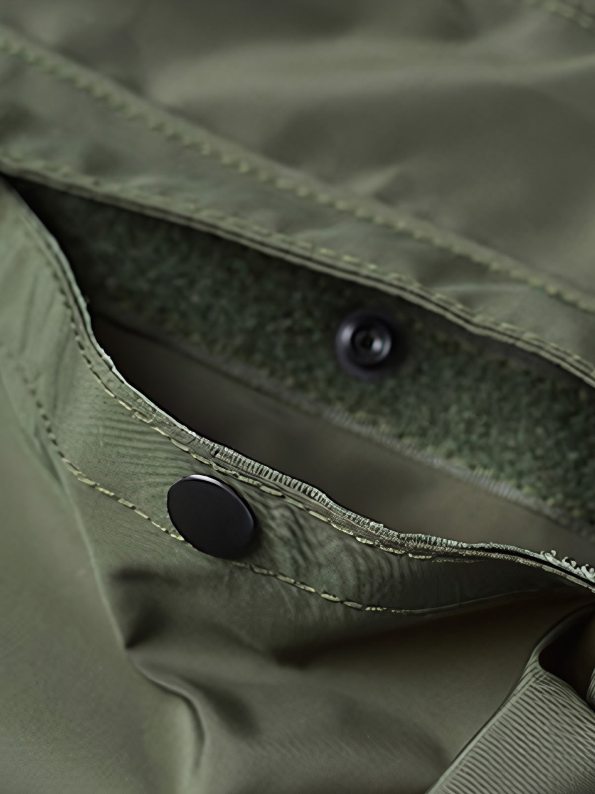 製品画像
1960年代のUSAFナイロンヘルメットバッグをリバイバルしたデザインの全体画像。防水性を備えた高密度ナイロン素材と多機能収納ポケットを特徴とするクラシカルなミリタリーバッグ。
詳細画像
フロント部分の立体収納ポケット、金属製フック、YKK製ナイロンファスナー、そしてキルティング加工された内部の中綿ディテールを強調したクローズアップ画像。