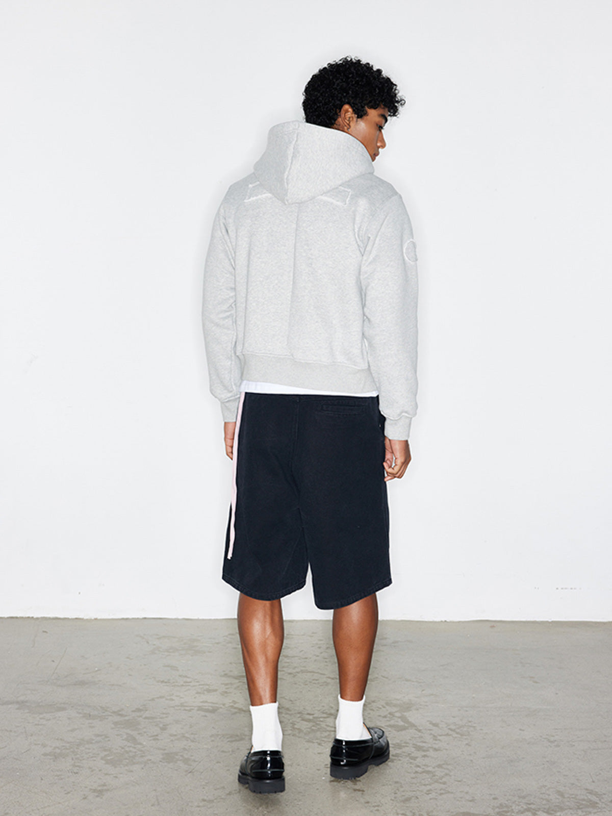 モデルがバッジパッチ付きフード付きジップアップパーカーを着用した画像