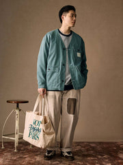 詳細画像
「ヘリンボーン生地のしっかりとしたテクスチャーとウォッシュ加工によるユーズド感、胸ポケットのラムウール織りディテールをクローズアップ。」
モデル画像
「インナーにシャツを合わせて着用したノーカラーフィッシングジャケット。ルーズフィットのシルエットがレイヤードスタイルを引き立てるヴィンテージ風コーディネート。」