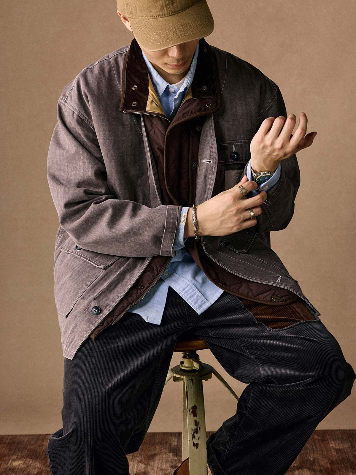 詳細画像
「ヘリンボーン生地のしっかりとしたテクスチャーとウォッシュ加工によるユーズド感、胸ポケットのラムウール織りディテールをクローズアップ。」
モデル画像
「インナーにシャツを合わせて着用したノーカラーフィッシングジャケット。ルーズフィットのシルエットがレイヤードスタイルを引き立てるヴィンテージ風コーディネート。」