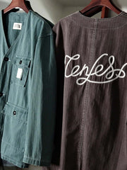 製品画像
「ヴィンテージ加工を施したノーカラーフィッシングジャケット全体イメージ。1950年代のフィッシングカーディガンからインスパイアされ、ウォッシュ加工で自然な色褪せ感を表現した一着。」
詳細画像
「ヘリンボーン生地のしっかりとしたテクスチャーとウォッシュ加工によるユーズド感、胸ポケットのラムウール織りディテールをクローズアップ。」