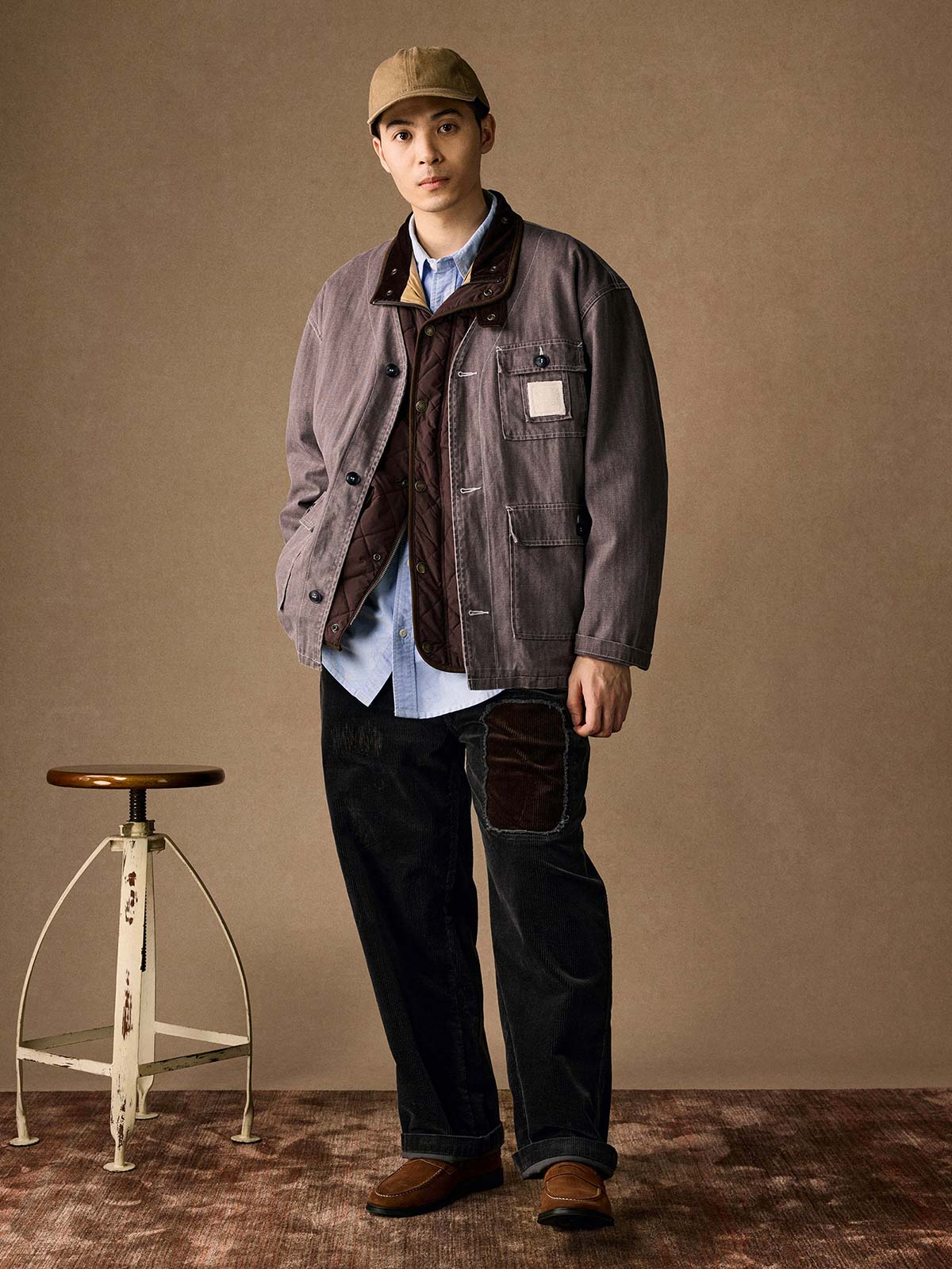 詳細画像
「ヘリンボーン生地のしっかりとしたテクスチャーとウォッシュ加工によるユーズド感、胸ポケットのラムウール織りディテールをクローズアップ。」
モデル画像
「インナーにシャツを合わせて着用したノーカラーフィッシングジャケット。ルーズフィットのシルエットがレイヤードスタイルを引き立てるヴィンテージ風コーディネート。」