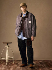 詳細画像
「ヘリンボーン生地のしっかりとしたテクスチャーとウォッシュ加工によるユーズド感、胸ポケットのラムウール織りディテールをクローズアップ。」
モデル画像
「インナーにシャツを合わせて着用したノーカラーフィッシングジャケット。ルーズフィットのシルエットがレイヤードスタイルを引き立てるヴィンテージ風コーディネート。」