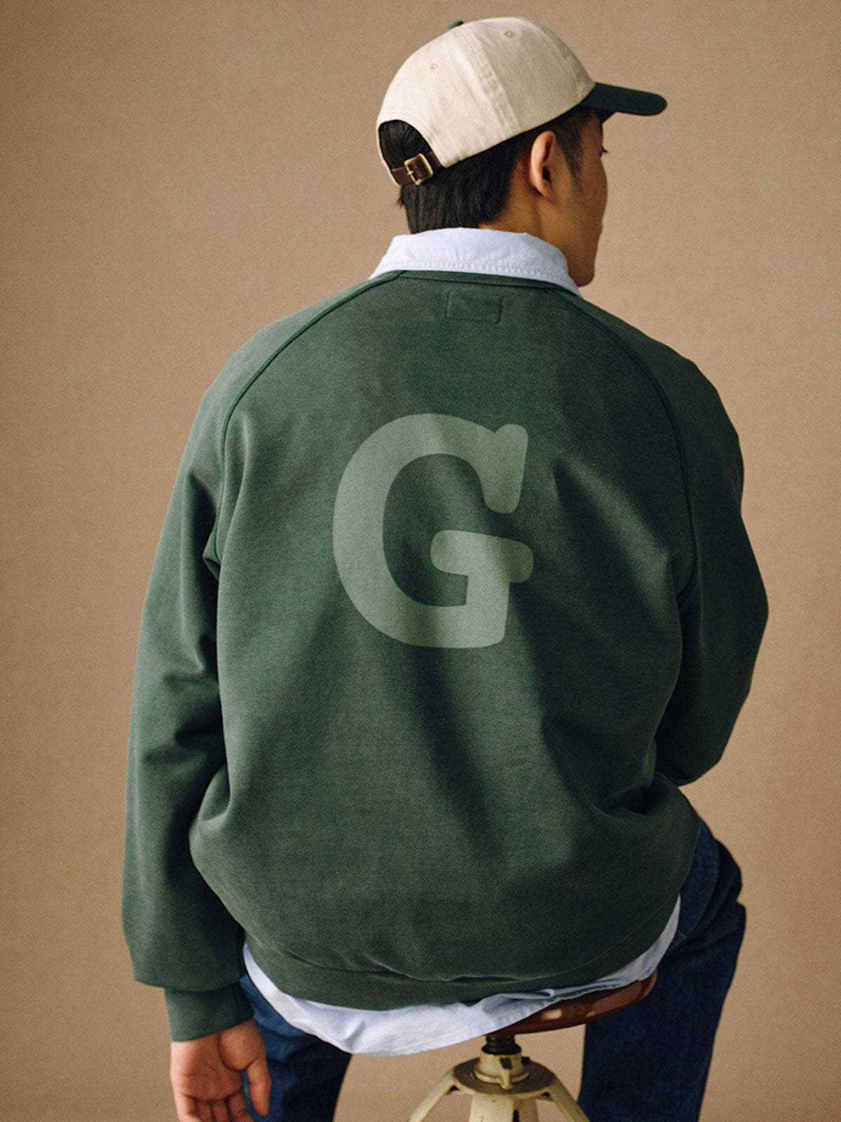 詳細画像
「胸元の英文字プリントとスノーウォッシュ加工による色落ち感が際立つ生地のディテールクローズアップ。柔らかな肌触りと褪色の質感が魅力。」
モデル画像
「モデルがピンクベージュの色落ち加工スウェットを着用し、カジュアルパンツと合わせたレトロでスポーティなヴィンテージ風コーディネート。」